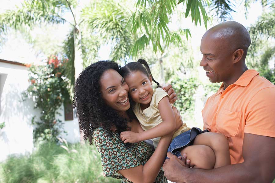 Parents holding their young daughter knowing her future is protected with their whole life insurance in San Marcos.