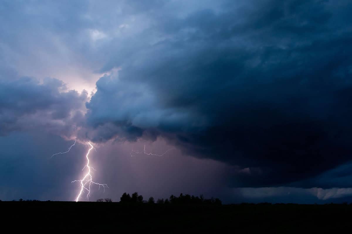 A dramatic sky filled with dark clouds and a bright lightning bolt striking down towards the horizon.